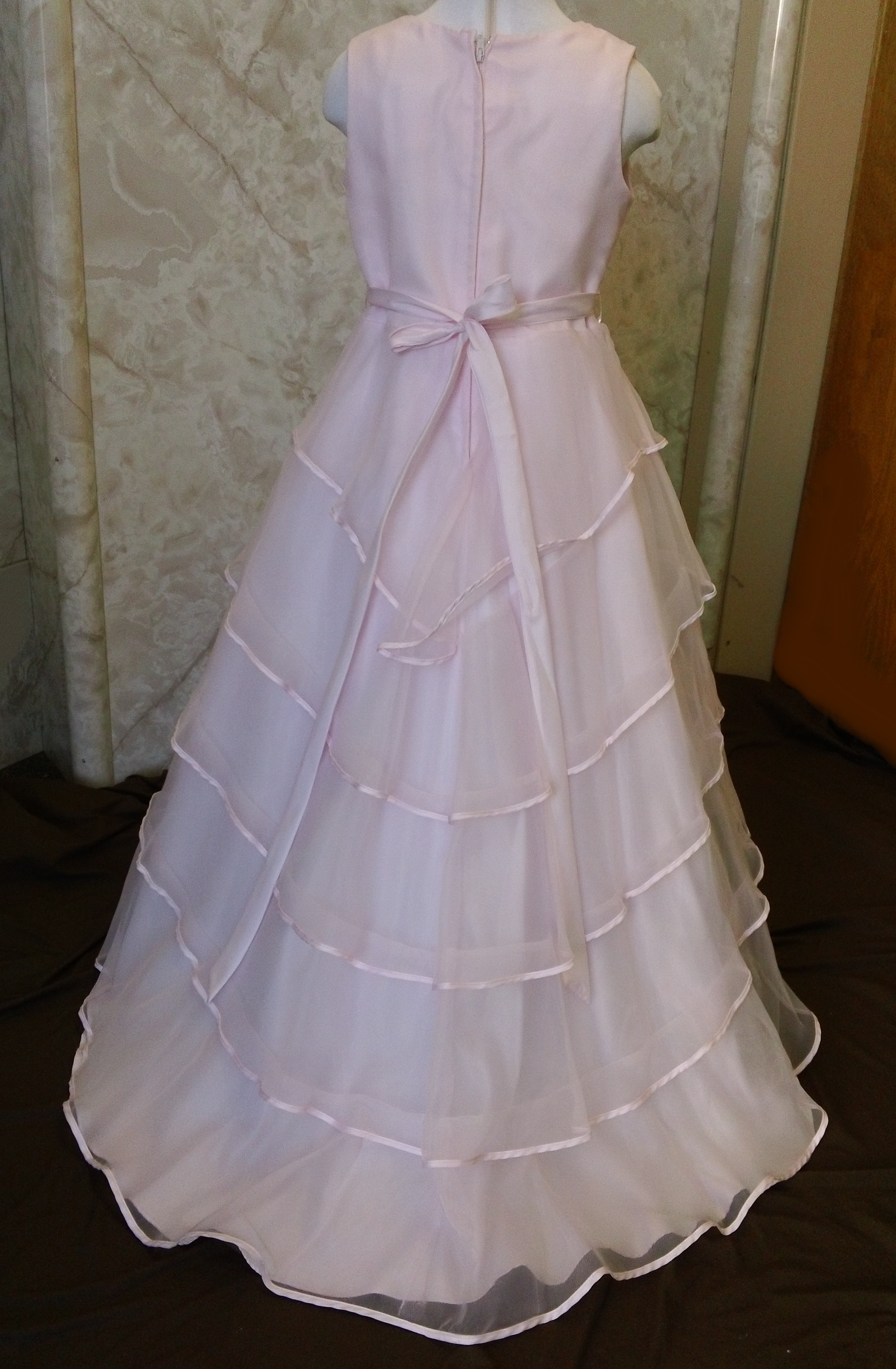 Long sleeveless girls pink dress with 5 tier skirt.  Zipper back, with tie sash.