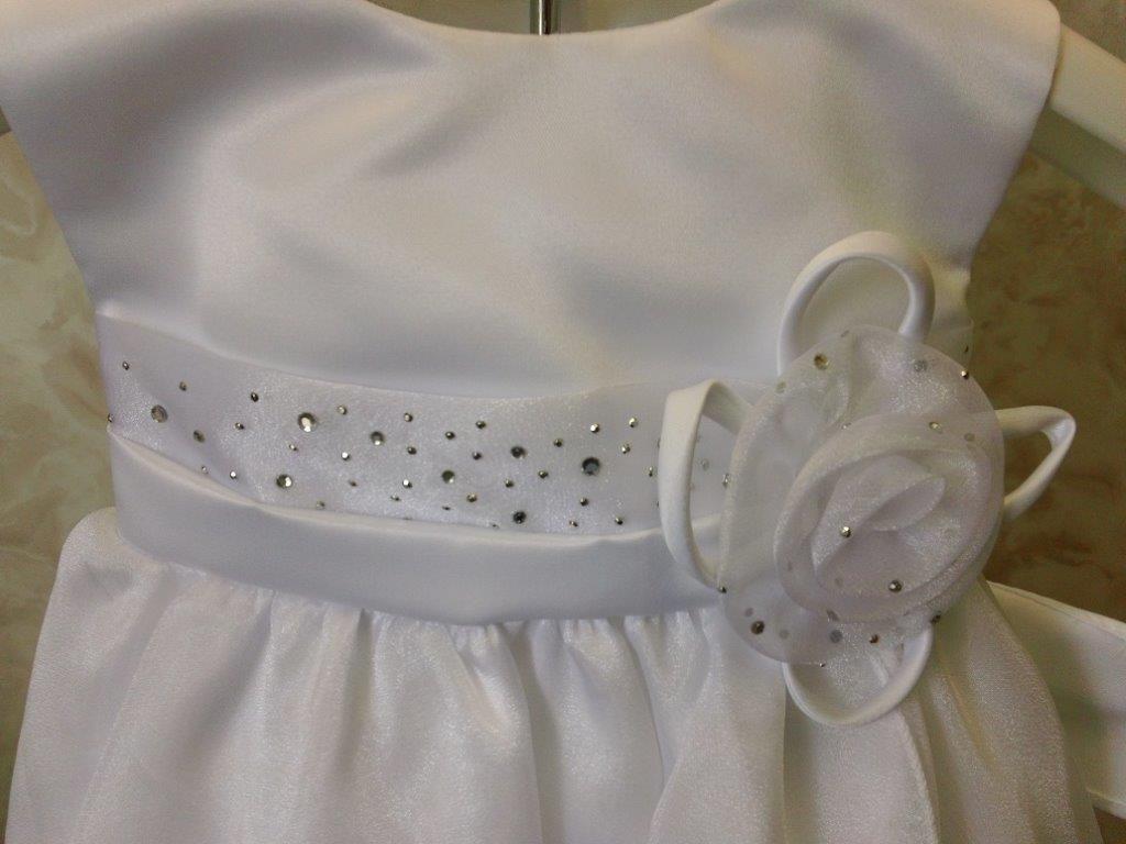 white infant dress with sequins and ribbon flower